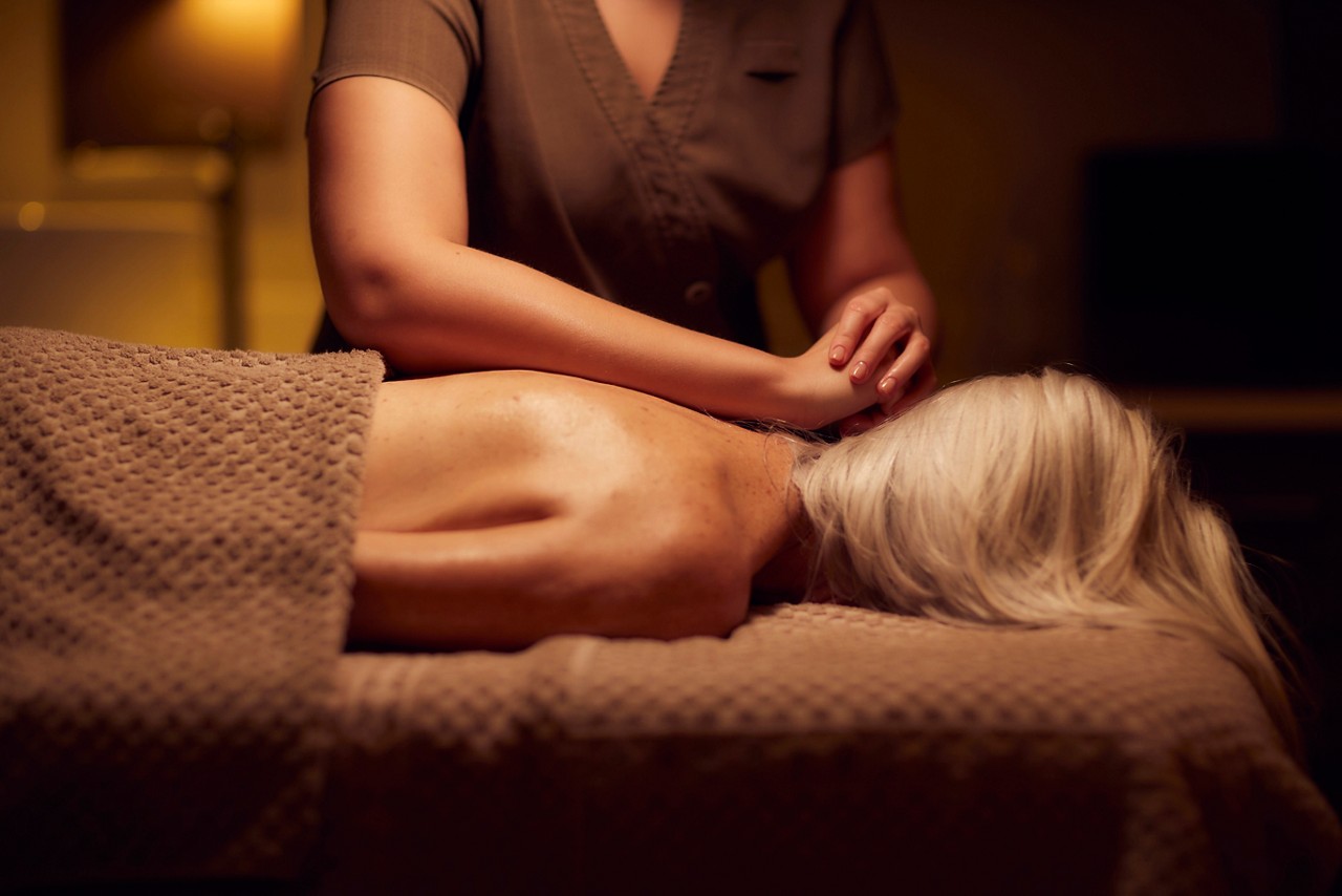 Spa therapist giving a woman a body brush treatment.