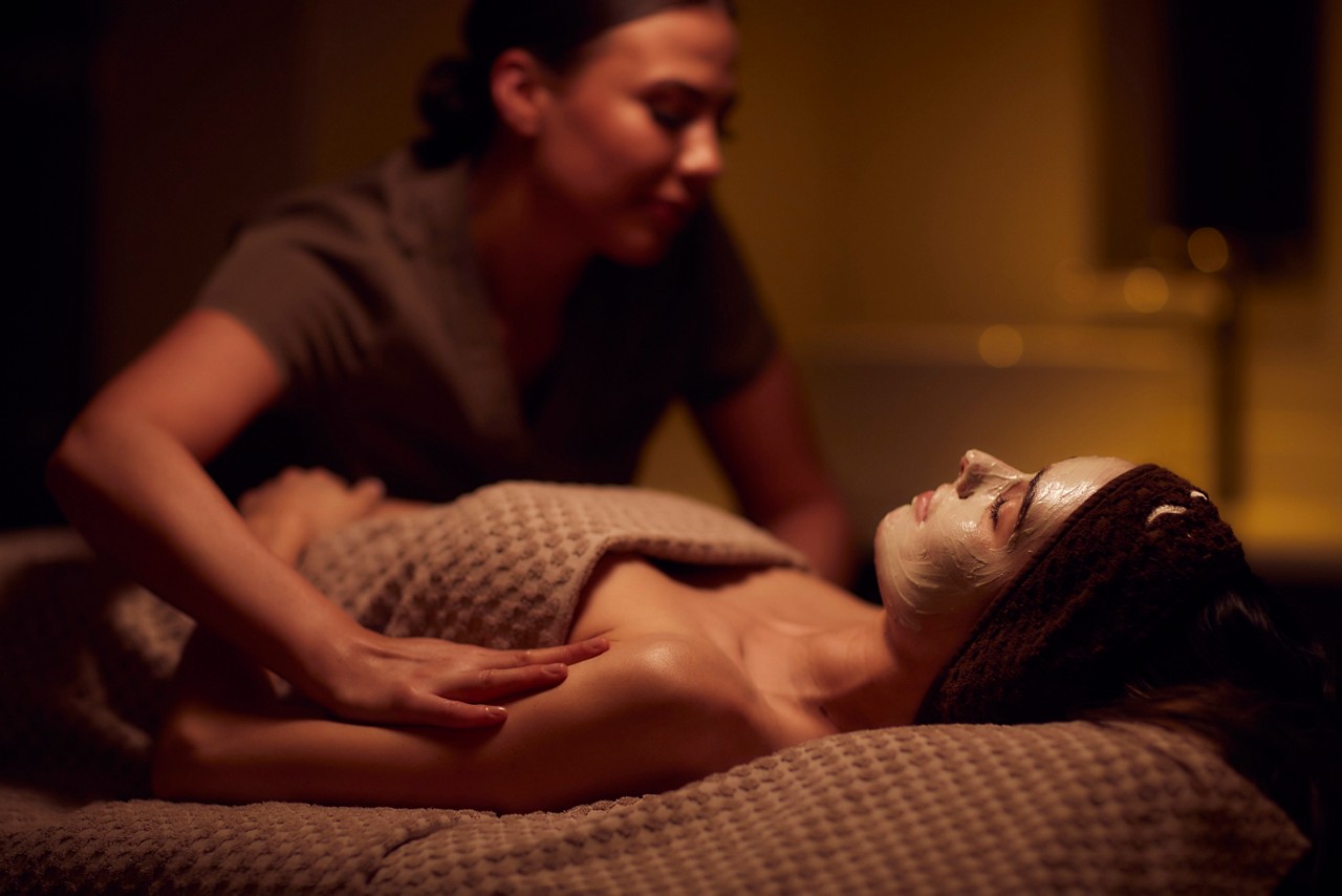 Spa therapist giving a woman a face mask treatment.