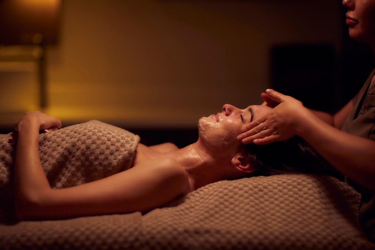 Spa therapist giving a woman a facial treatment.