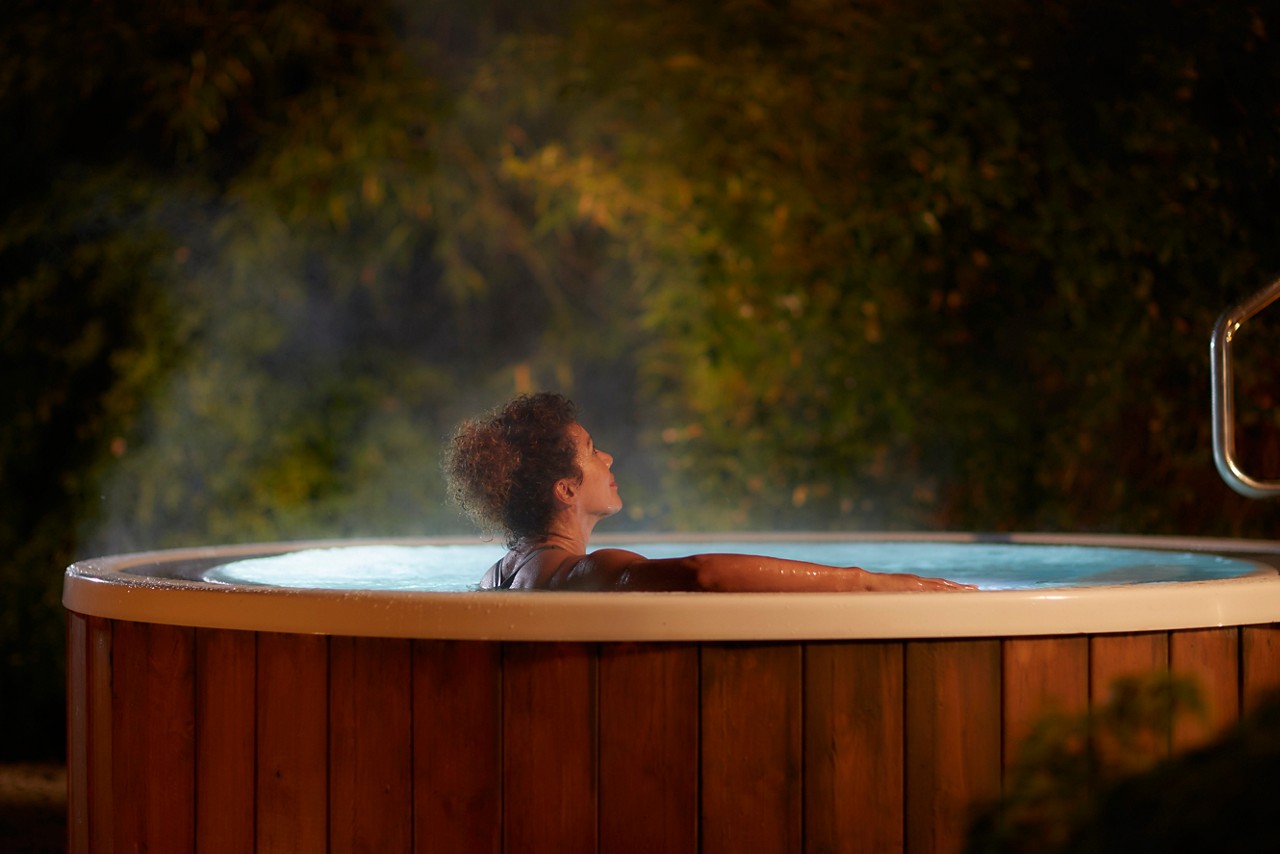 Woman soaking in a bubbling outdoor hot tub.