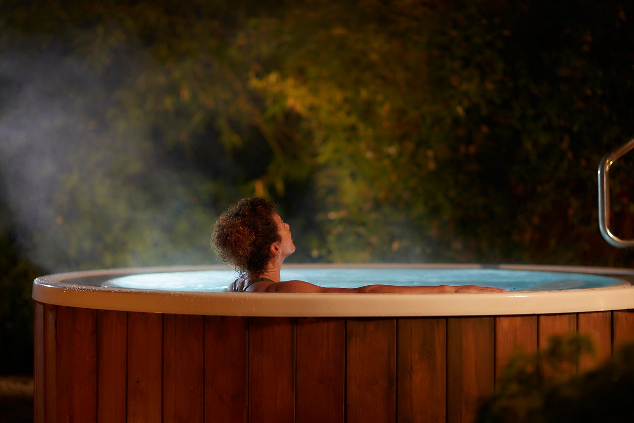 Woman soaking in a bubbling outdoor hot tub.