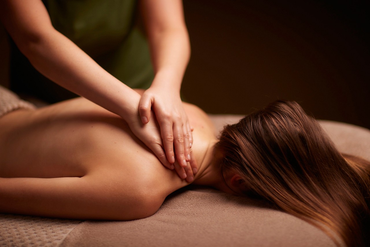 Spa therapist giving a woman a relaxing back massage body treatment.