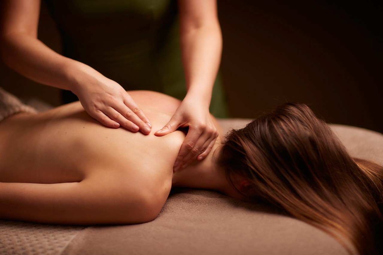 Spa therapist giving a woman a relaxing back massage body treatment.