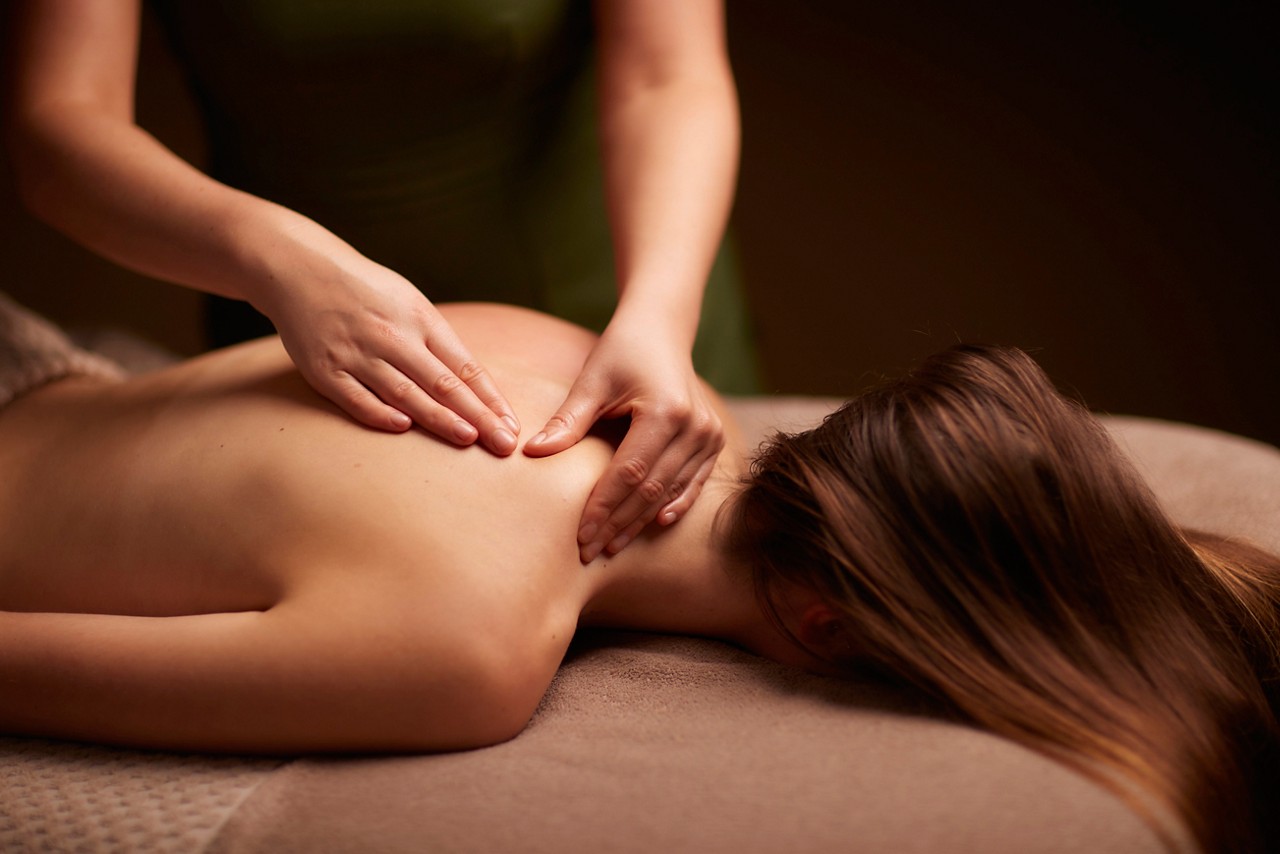 Spa therapist giving a woman a relaxing back massage body treatment.