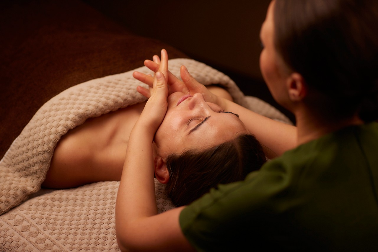 Spa therapist giving a woman a facial treatment.